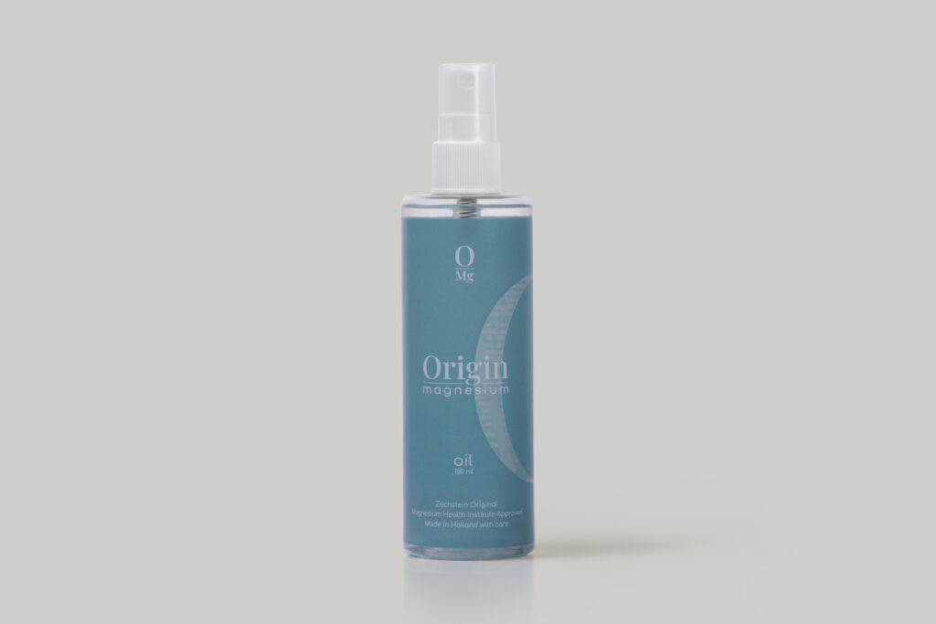 A blue bottle labeled "Origin Magnesium Oil" with a spray nozzle. The design includes a crescent shape and text indicating it is from Zechstein Original and made in Holland. The bottle stands on a plain, light gray background.