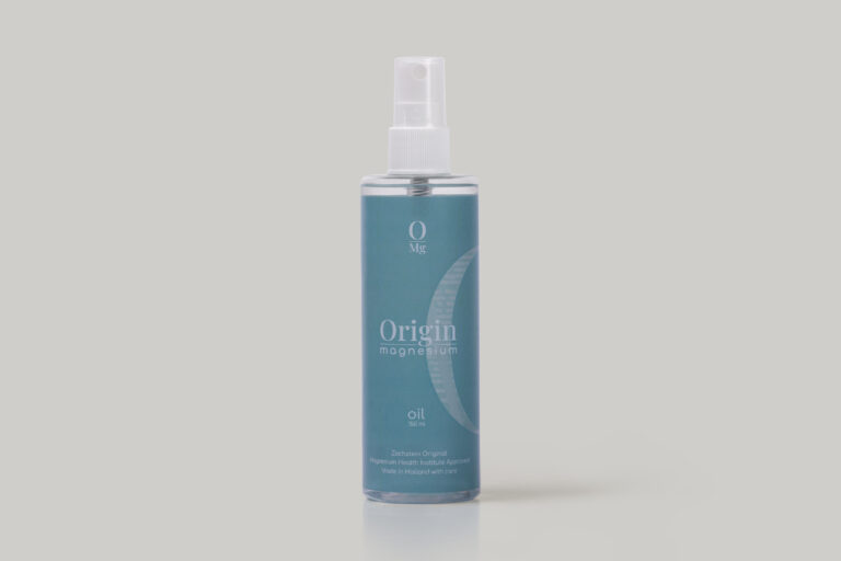 A blue bottle labeled "Origin Magnesium Oil" with a spray nozzle. The design includes a crescent shape and text indicating it is from Zechstein Original and made in Holland. The bottle stands on a plain, light gray background.